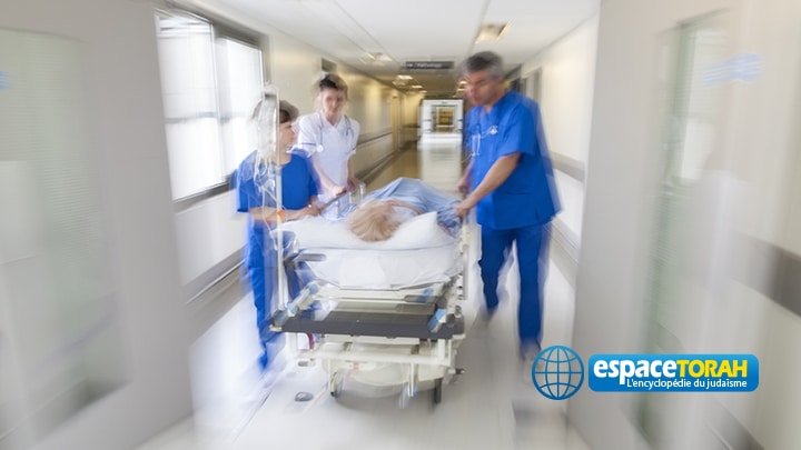 A motion blurred photograph of a patient on stretcher or gurney being pushed at speed through a hospital corridor by doctors & nurses to an emergency room